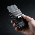 Thumb pushing the lever so cards fan out of the carbon fibre slim wallet